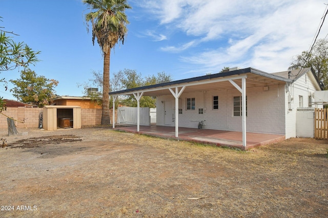 rear view of property featuring a patio area and a storage unit