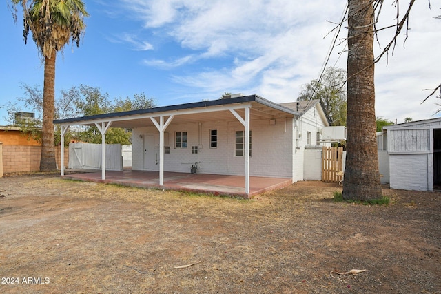 rear view of property featuring a patio area and a shed