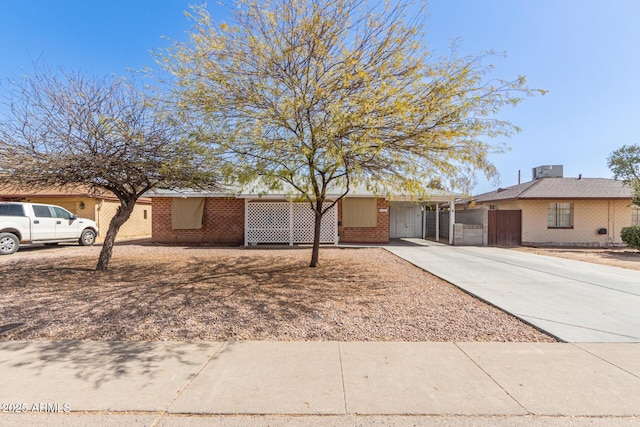 ranch-style house with a gate, brick siding, and driveway