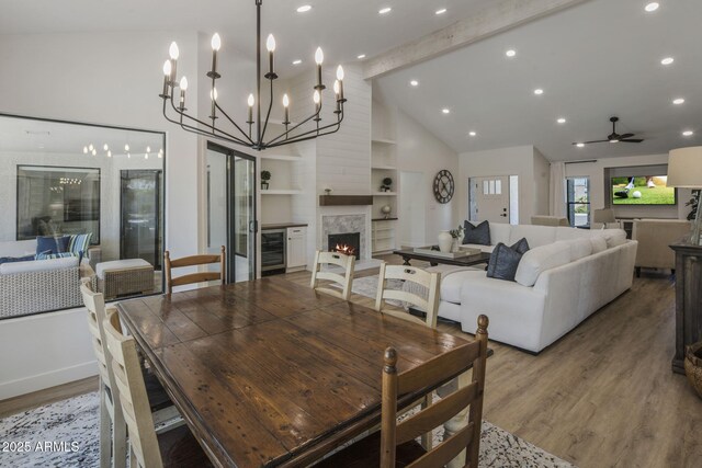 dining room featuring a warm lit fireplace, wine cooler, wood finished floors, beam ceiling, and recessed lighting