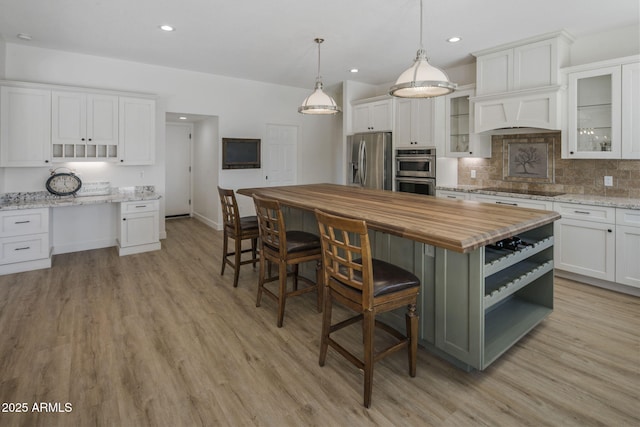 kitchen featuring appliances with stainless steel finishes, butcher block countertops, white cabinetry, and tasteful backsplash