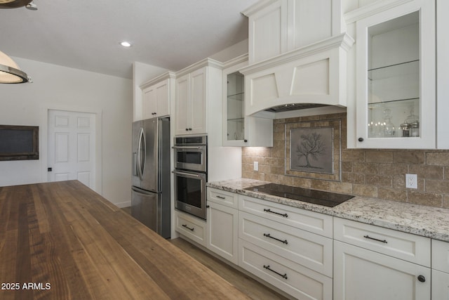 kitchen with tasteful backsplash, butcher block counters, appliances with stainless steel finishes, glass insert cabinets, and white cabinetry