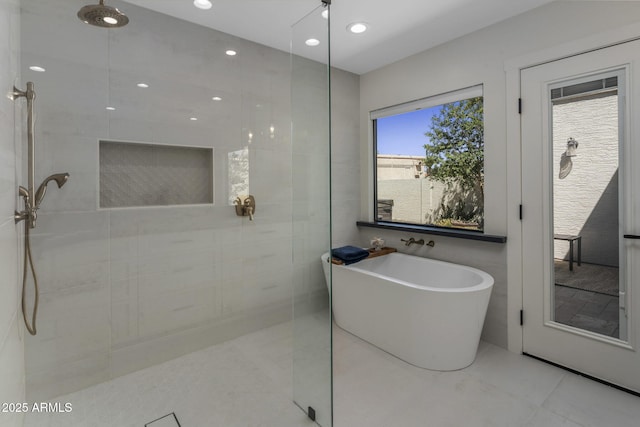 full bath featuring a walk in shower, a freestanding tub, and tile walls