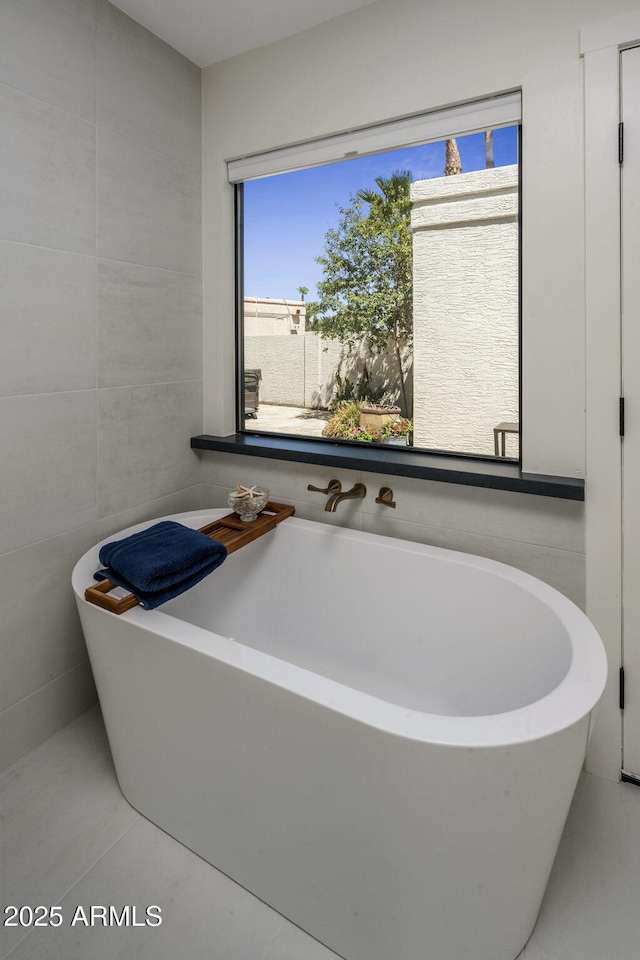 bathroom with a freestanding tub and tile walls