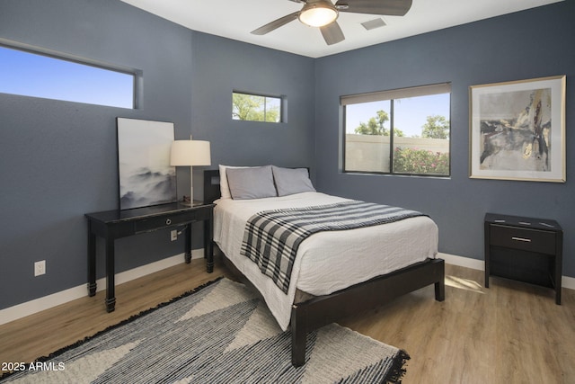 bedroom featuring visible vents, ceiling fan, baseboards, and wood finished floors