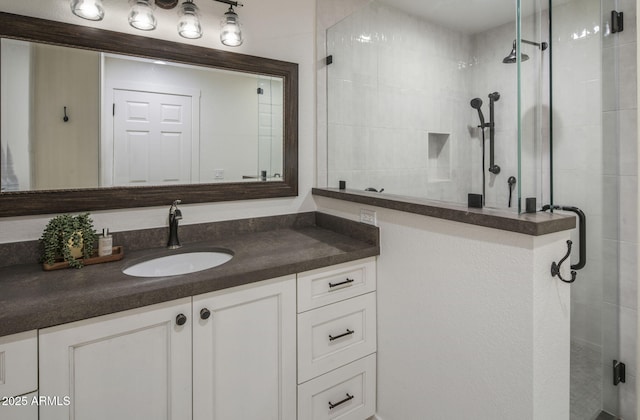 bathroom with a tile shower and vanity