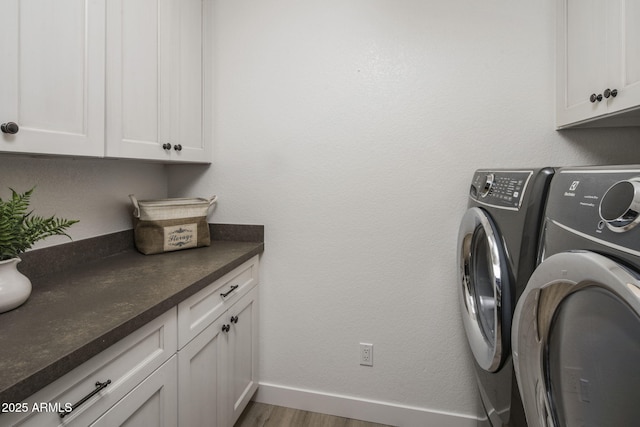 laundry area featuring cabinet space, baseboards, washer and clothes dryer, and wood finished floors