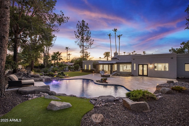 pool at dusk featuring a patio area and french doors