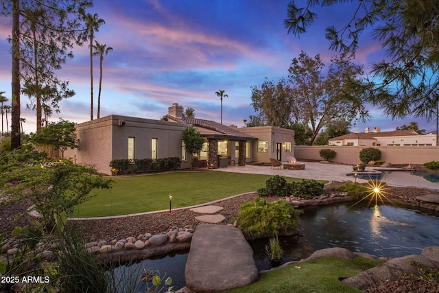 back of property featuring a lawn, a patio, a chimney, fence, and stucco siding