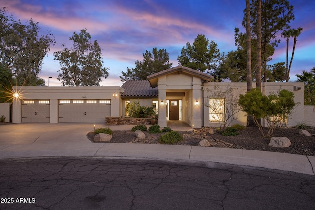 view of front of property with a garage, a tiled roof, driveway, and stucco siding