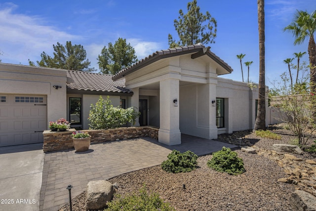 view of front of home with a tile roof, an attached garage, and stucco siding