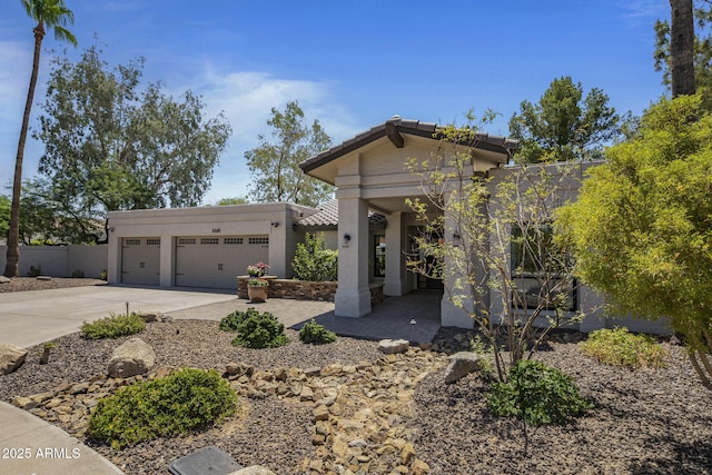 view of front of house with concrete driveway, an attached garage, a tile roof, and stucco siding