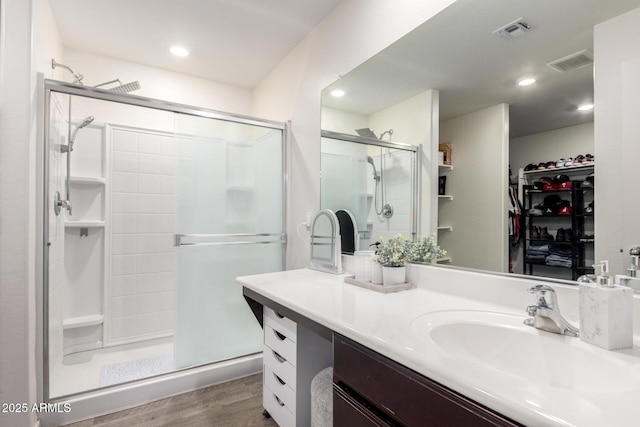 bathroom with hardwood / wood-style floors, a shower with door, and vanity