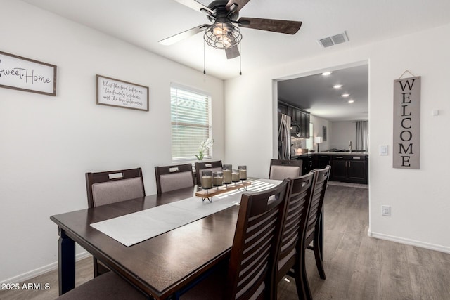 dining room with ceiling fan, sink, and wood-type flooring