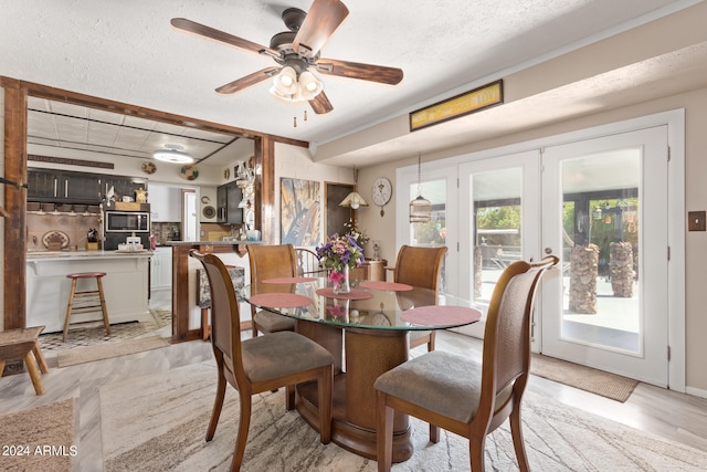 dining room with ceiling fan, french doors, light hardwood / wood-style flooring, and a textured ceiling