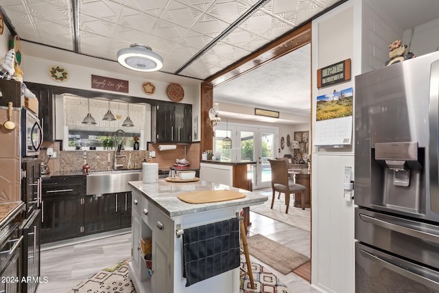 kitchen featuring a kitchen island, french doors, appliances with stainless steel finishes, backsplash, and sink