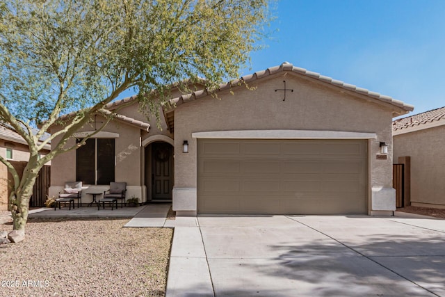 mediterranean / spanish home featuring stucco siding, a garage, concrete driveway, and a tiled roof