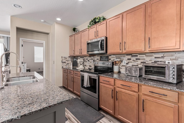 kitchen with a sink, dark stone countertops, tasteful backsplash, appliances with stainless steel finishes, and a toaster