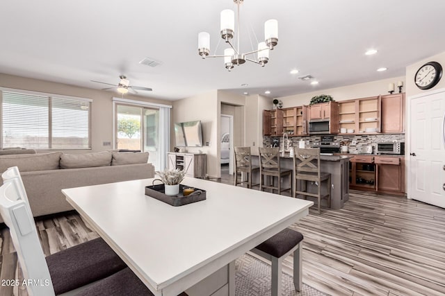 dining space with a toaster, recessed lighting, ceiling fan with notable chandelier, and light wood finished floors