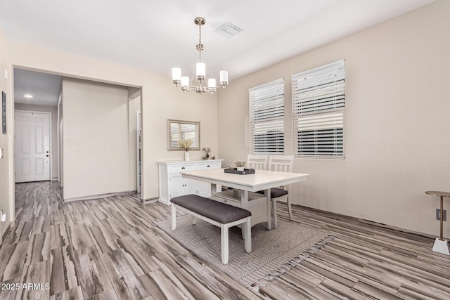 dining room with a chandelier, visible vents, light wood-style flooring, and baseboards