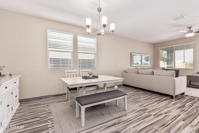 dining room featuring visible vents, light wood-style floors, and ceiling fan with notable chandelier