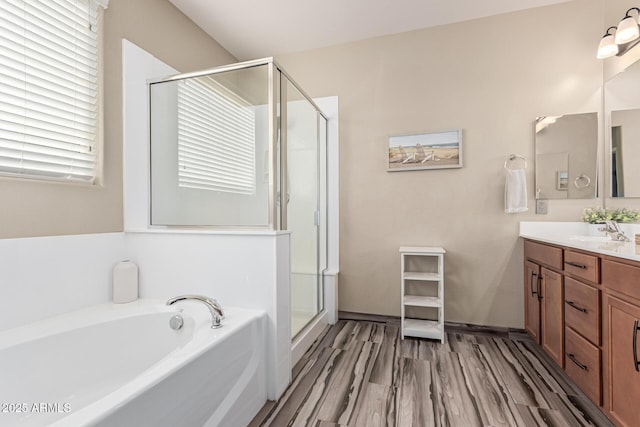 full bathroom featuring a sink, wood finished floors, a shower stall, double vanity, and a bath