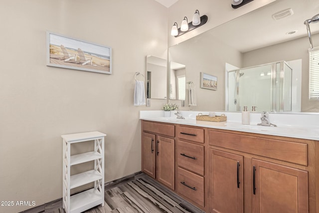 full bathroom featuring visible vents, a stall shower, a sink, wood finished floors, and double vanity