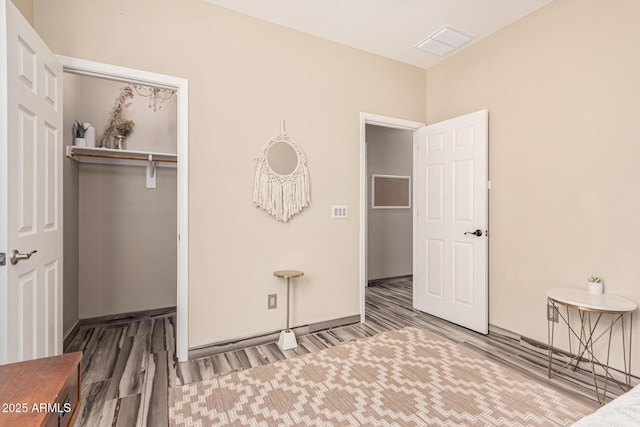 bedroom with a closet, visible vents, baseboards, and wood finished floors