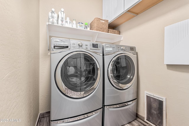 laundry room featuring cabinet space, independent washer and dryer, and a textured wall