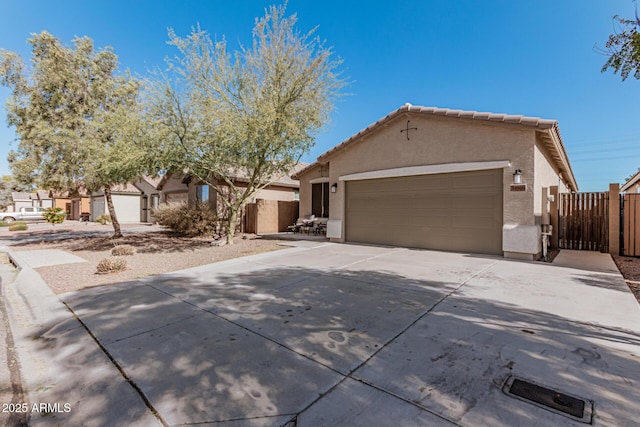 view of front of property with fence, stucco siding, concrete driveway, a garage, and a tiled roof