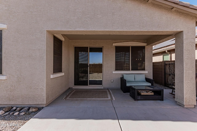 doorway to property with stucco siding, a tile roof, a patio, and fence