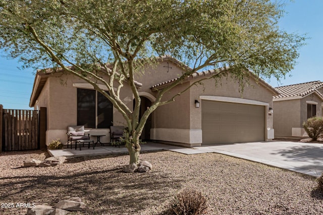 view of front facade featuring concrete driveway, a tiled roof, a garage, and stucco siding