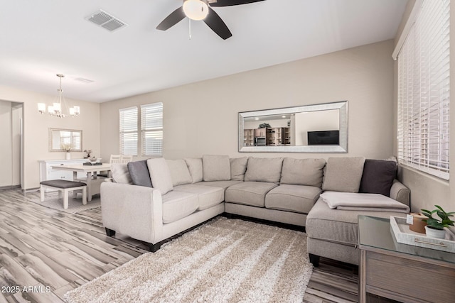 living area featuring visible vents, wood finished floors, and ceiling fan with notable chandelier