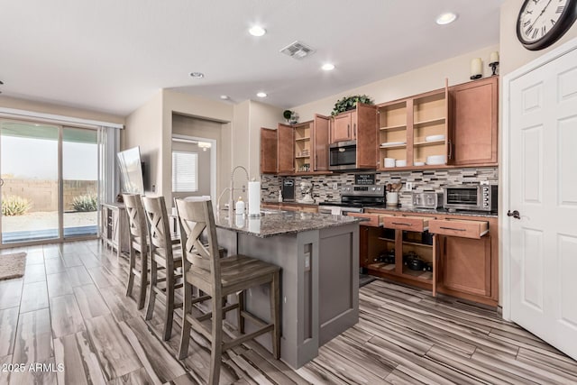 kitchen featuring tasteful backsplash, open shelves, brown cabinets, stainless steel appliances, and a sink