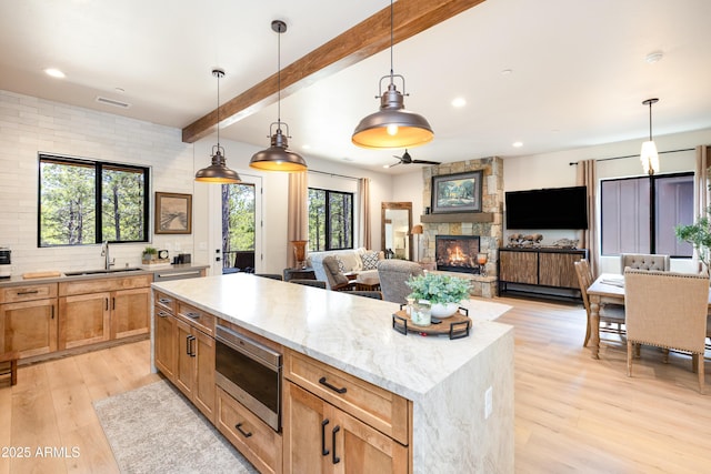 2582 S Cottonrose Ln, Flagstaff, AZ 86001 - kitchen with a sink, a fireplace, light wood-type flooring, stainless steel microwave, and beamed ceiling