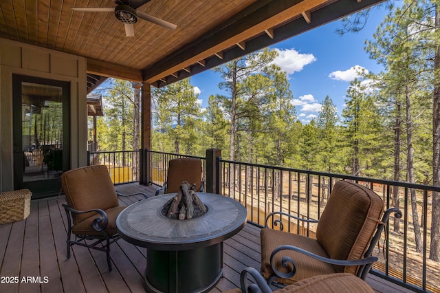 2582 S Cottonrose Ln, Flagstaff, AZ 86001 - wooden deck featuring ceiling fan, an outdoor fire pit, and a view of trees