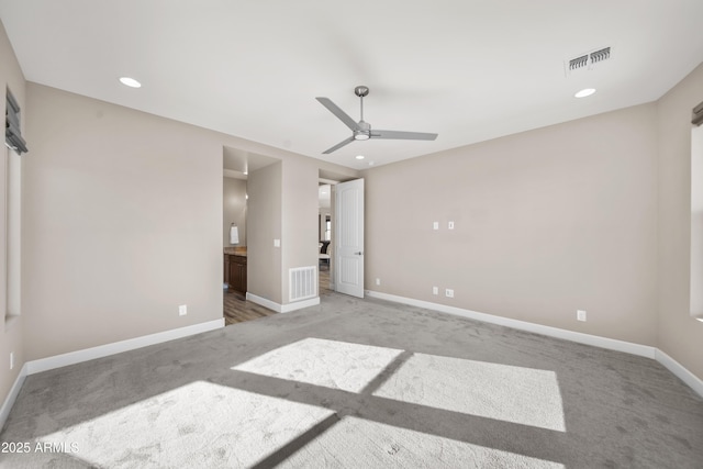 unfurnished bedroom featuring ceiling fan, light colored carpet, and ensuite bath