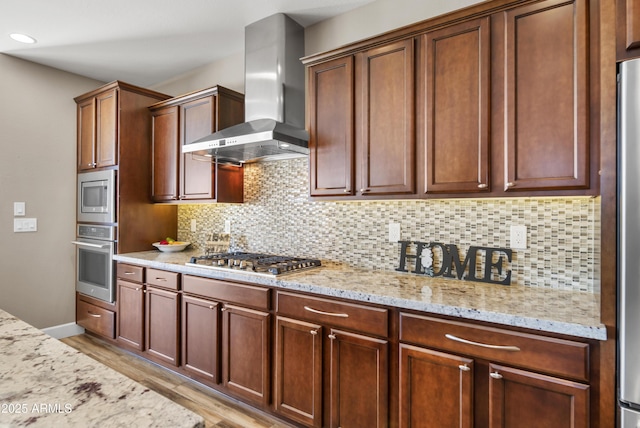 kitchen featuring stainless steel appliances, light hardwood / wood-style floors, light stone counters, and wall chimney range hood