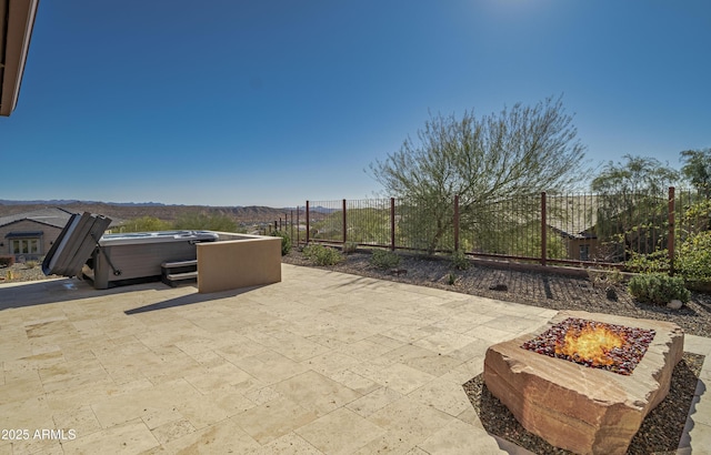 view of patio / terrace featuring a hot tub and an outdoor fire pit