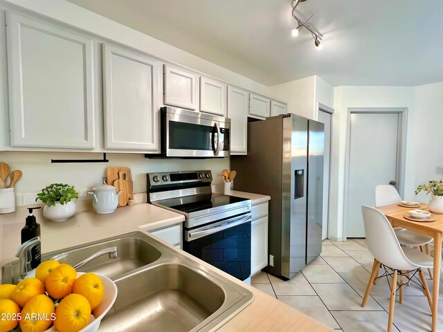 7801 N 44th Dr Unit 1180, Glendale, AZ 85301 - kitchen with stainless steel appliances, light tile patterned flooring, light countertops, rail lighting, and white cabinetry