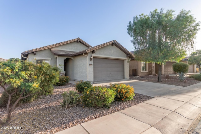 single story home with an attached garage, concrete driveway, a tiled roof, and stucco siding