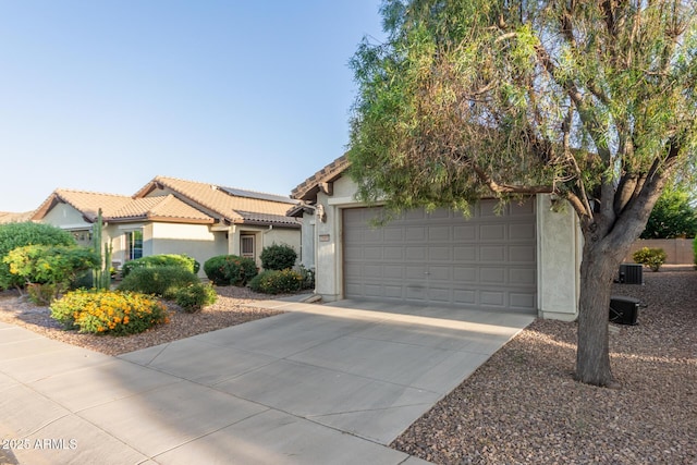 view of front of property featuring roof mounted solar panels, central AC unit, concrete driveway, stucco siding, and a tile roof