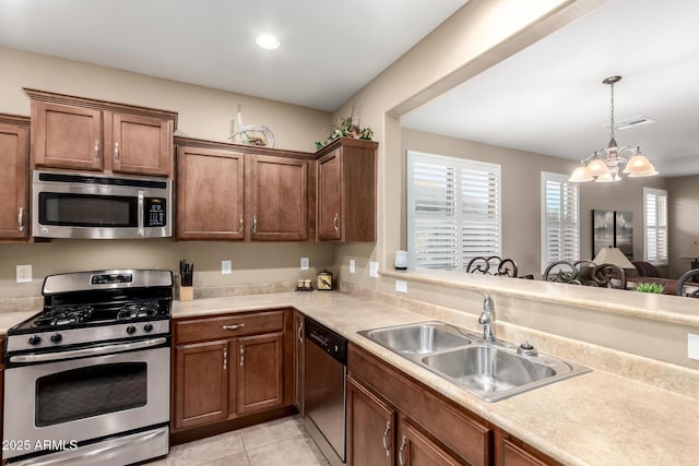 kitchen featuring stainless steel appliances, light countertops, a sink, and an inviting chandelier