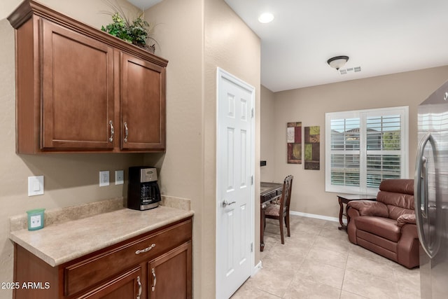 interior space with stainless steel fridge, light tile patterned flooring, open floor plan, visible vents, and light countertops
