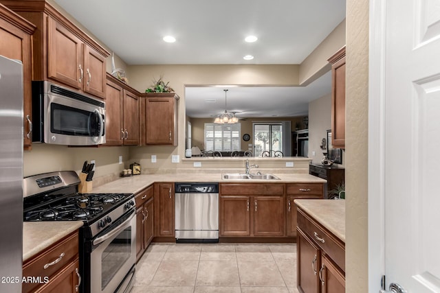kitchen with a sink, brown cabinetry, light tile patterned floors, light countertops, and appliances with stainless steel finishes