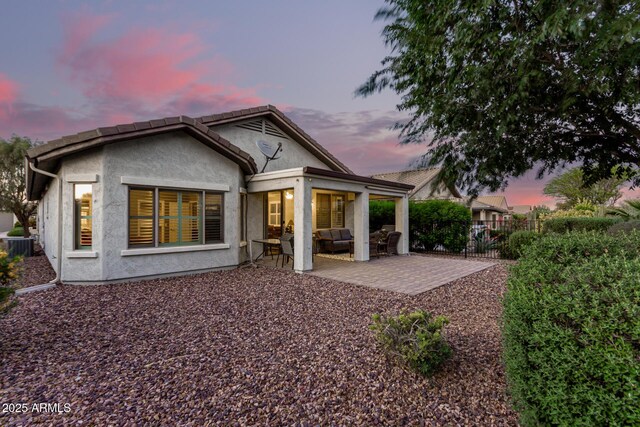 rear view of property with outdoor lounge area, fence, central AC, stucco siding, and a patio