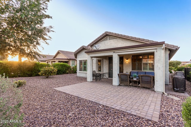 rear view of house featuring stucco siding, outdoor lounge area, and a patio area