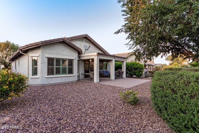 back of property with stucco siding, a tile roof, fence, and a patio