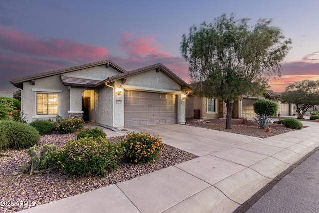 ranch-style home with a tiled roof, stone siding, concrete driveway, an attached garage, and stucco siding