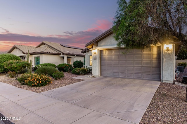 view of front of house with concrete driveway, a tiled roof, an attached garage, cooling unit, and stucco siding